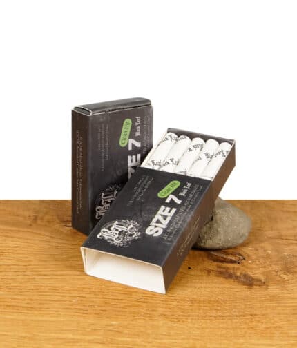 Zwei Packungen Black Leaf Size 7 Aktivkohlefilter Clean Hit, eine liegend und geöffnet, auf einem Holztisch mit einem Stein.