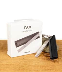 PAX Multi-Tool in der Originalverpackung, auf einem Holztisch platziert, zusammen mit dem Multi-Tool selbst und einem Schlüsselring.