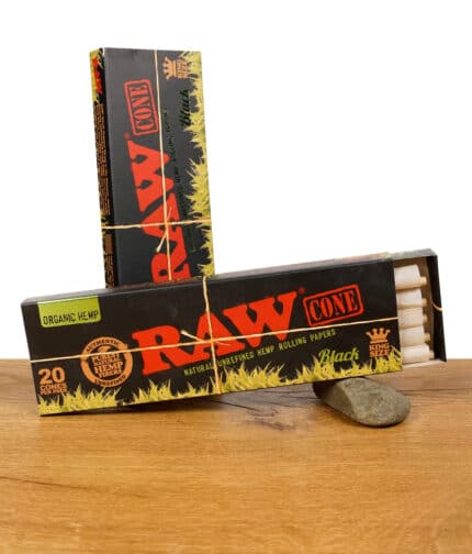 Geöffnete und geschlossene Packung RAW Black Organic King Size Pre-Rolled Cones auf einem Holzuntergrund.
