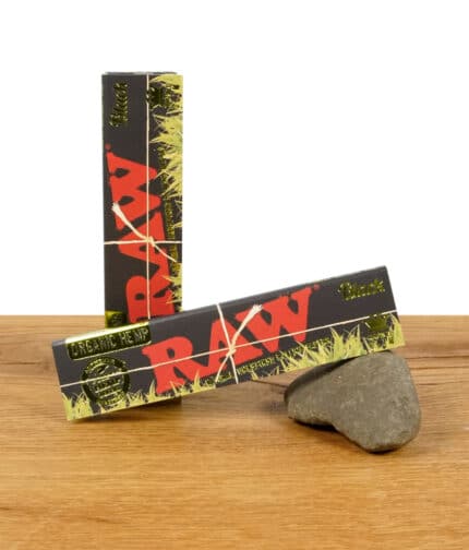 Zwei Packungen RAW Black Organic Hemp Rolling Papers im King Size Slim Format, auf einem Stein präsentiert